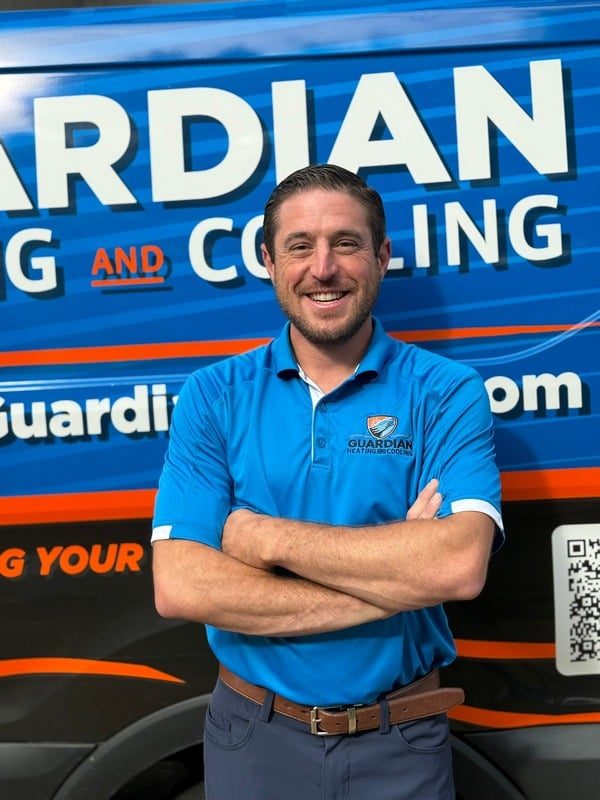 Guardian Heating and Cooling technician standing in front of a branded service van